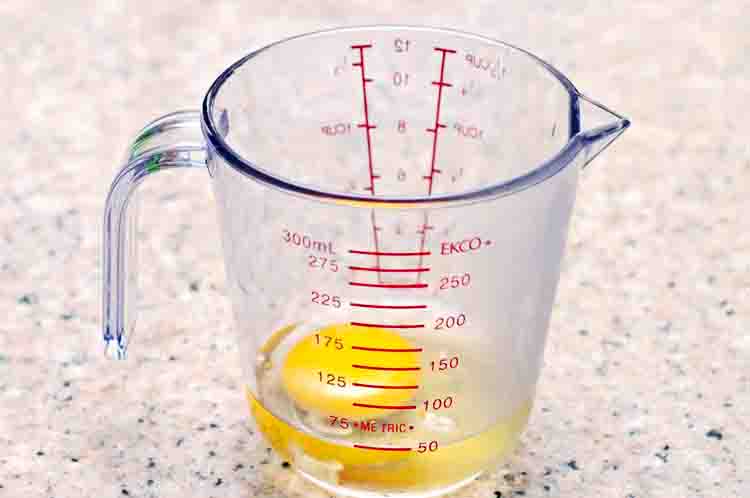 Mengocok telur dalam gelas ukur -  Cara membuat adonan sosis telur  dilakukan dengan mengocok telur dalam gelas ukur